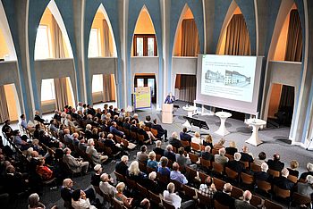 Personen in einem Saal bei einer Präsentation