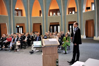 Ein Mann am Rednerpult in einer Aula.