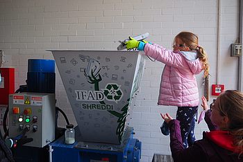 Kinder legen Objekte in einen großen Schredder