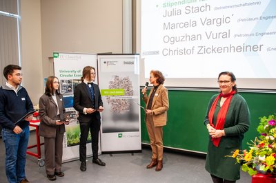 Gruppe von fünf Personen stehen im Hörsaal bei einer Urkundenübergabe.