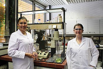 Zwei Personen mit Laborkitteln und Schutzbrillen in einem Labor