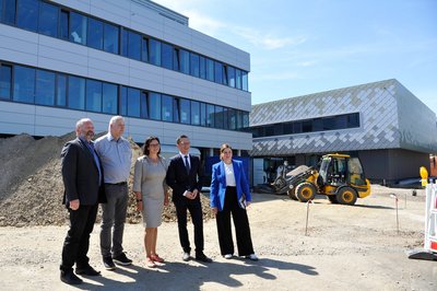 Gruppe von fünf Personen steht repräsentativ vor einem Neubau. 