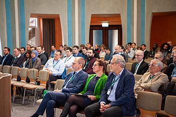 Ein Publikum sitzt in Reihen und schaut nach vorne. 