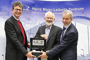 Drei Personen mit einer Trophäe des MLZ