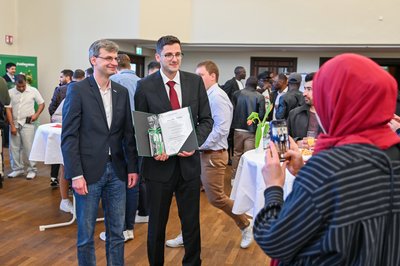 Professor posiert mit Absolventen. 