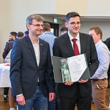 Professor posiert mit Absolventen. 