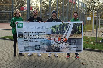 Vier Personen halten ein TU Clausthal-Banner