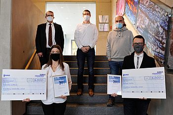 Menschen mit einer Urkunde und einem Scheck stehen auf einer Treppe 