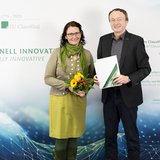 Die Clausthaler Universitätspräsidentin und ein neuer Professor stehen vor einer Wand mit Logo der TU Clausthal.