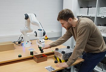 Person arbeitet mit einem Roboterarm 