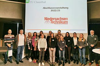 Personen stehen auf der Bühne vor der Projektionsfläche