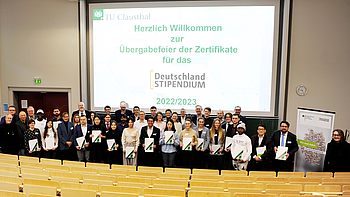 Personen stehen auf der Bühne vor der Projektionsfläche 