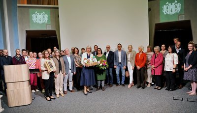 Eine Gruppe von rund 30 Personen übergibt einer Frau ein Geschenk. 
