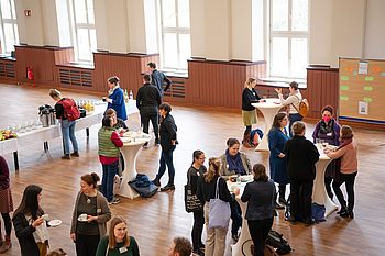 Menschen an kleinen runden Tischen auf einer Messe