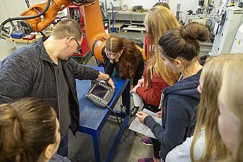 Studierende beobachten ein mit einer Maschine verknüpftes Gerät