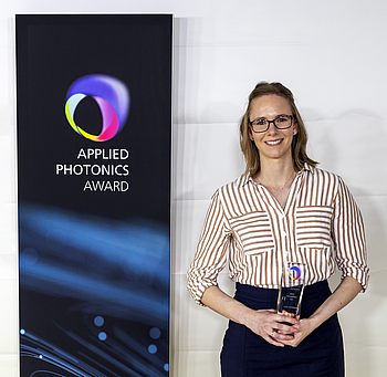 Eine Person hält einen Pokal vom "Applied Photonics Award" in der Hand