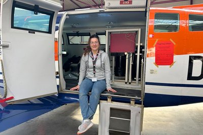 Eine Frau sitzt in der Tür zu einem Flugzeug. 