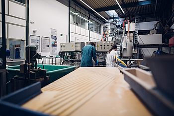 Zwei Personen in einer Werkstatt bedienen eine Maschine 