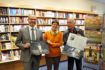 Drei Personen in einem Buchladen mit Kalendern in der Hand