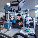 Zwei Wissenschaftler beschäftigen sich mit einer Roboteranlage.
