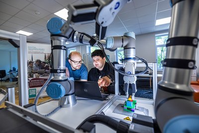 Zwei Wissenschaftler beschäftigen sich mit einer Roboteranlage.