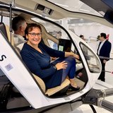 Eine Frau sitzt in einem kleinen Hubschrauber, der noch am Boden steht. 