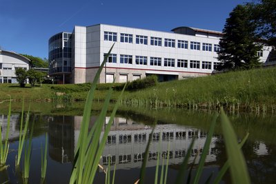 Fotos eines Forschungsinstituts mit einem Teich im Vordergrund.