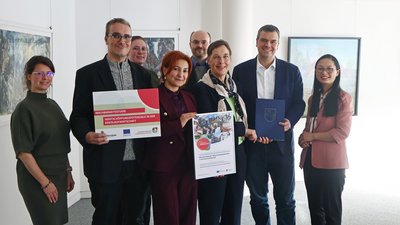 Gruppenbild mit acht Personen, zwei von ihnen haben ein Poster in der Hand.