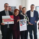 Gruppenbild mit acht Personen, zwei von ihnen haben ein Poster in der Hand.
