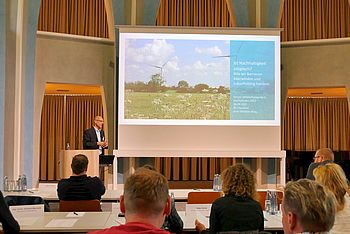 Person an einem Rednerpult hält eine Präsentation