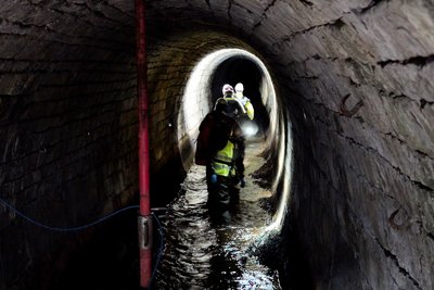 Eine Gruppe wandert durch einen Stollen, der zum Teil mit Wasser gefüllt ist.