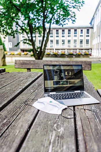 Laptop und eine Maske auf einem Tisch