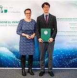 Die Tu-Präsidentin und Prof. Paek stehen vor der TU-Fotowand mit der Urkunde.