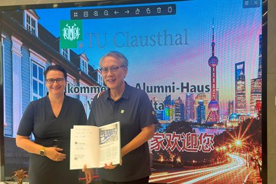 Eine Frau und ein Mann präsentieren ein Buch, genauer gesagt die Festschrift der TU Clausthal.