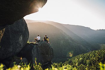 Zwei Personen sitzen auf einem großen Felsen