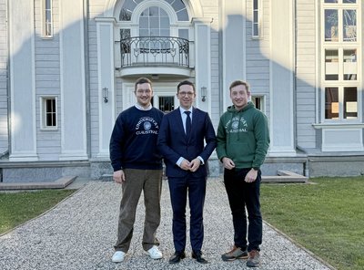 Drei Männer stehen vor einem weißen Gebäude. 