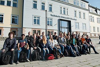 Studenten sitzen vor dem Hauptgebäude der TU Clausthal