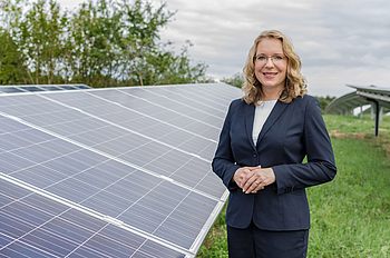 Eine Person steht neben einem Solarpanel 