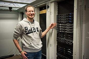 Eine Person steht neben einem Serverschrank