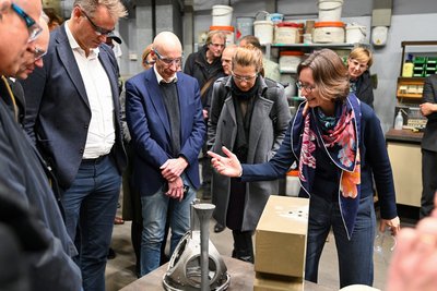 Eine Frau erklärt Personen ein Exponat in einer Technikumshalle. 