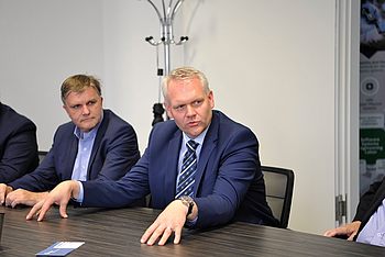 Eine Person mit den Händen auf dem Tisch spricht während einer Besprechung mit anderen 