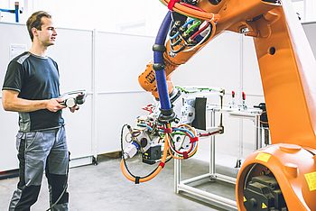 Eine Person arbeitet an einem Roboterarm