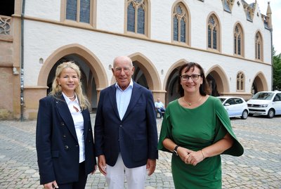 Zwei Frauen und ein Mann stehen vor dem historischen Rathaus der Stadt Goslar.
