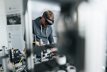 Person mit Brille arbeitet an einer Maschine 