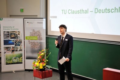 Student im feinen Anzug hält im Hörsaal eine Rede. 