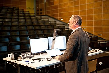 Ein Professor bei der Aufnahme einer Vorlesung in einem leeren Hörsaal