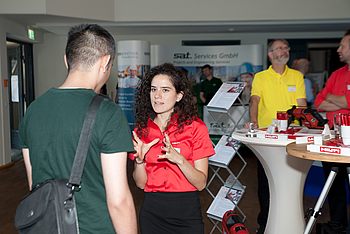 Person bei einer Messe erklärt jemandem etwas 