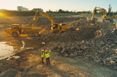 Baustelle mit einem Lkw und zwei Baggern.