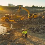 Baustelle mit einem Lkw und zwei Baggern.
