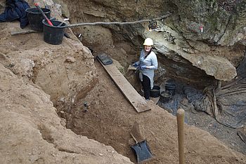 Eine Person steht während der Ausgrabung in einem Loch